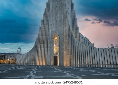 The Hallgrímskirkja in Reykjavik, Iceland, features a tall tower, basalt column facade, and stained glass window. The dramatic sky adds to the captivating atmosphere. - Powered by Shutterstock