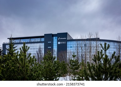 Reykjavik, Iceland - March 24, 2022: Headquarters Of Orkusalan Energy Supplier And Valholl Dental Clinic. Modern Glass Building Facade, Pine Trees In Foreground. 
