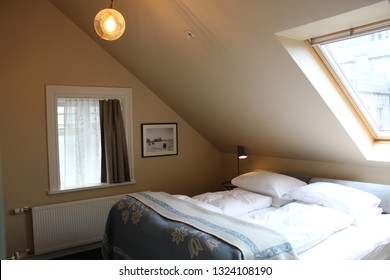 Reykjavik / Iceland - May 15 2018: Attic Apartment Bedroom Cozy / Cosy Bed Modern Interior Design With Slanted Roof And Skylight Window