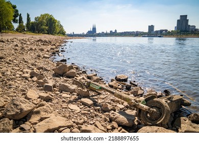 Rhine River, Cologne, Germany 10.08.2022: Dried Up Rhine River And Low Water Level, Due To Heat Wave, Cologne Cathedral In The Background, Discarded E-scooter In The Foreground