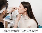 Rhinoplasty is reshaping nose surgery for change appearance of the nose and improve breathing. ENT doctor is touching nose and consulting girl patient in medical clinic before septoplasty surgery