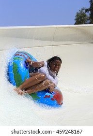 Rhodes, Greece-July 26,2016:Black cheerful girl  drive with tube on the rafting slide in the  Water park.Rafting slide is one of many popular game for adults and children in park