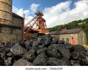 Rhondda Heritage Park, Wales - September 2017: Lumps of coal in a mine tram with the pithead of the former Lewis Merthyr  colliery in the background