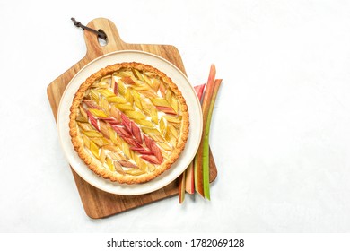 Rhubarb Open Faced Round Pie Served On A Wooden Cutting Board, Overhead View, Copy Space For A Text