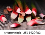 Rhubarb stalks on a wooden table close up. Ripe rhubarb stems cut with a knife