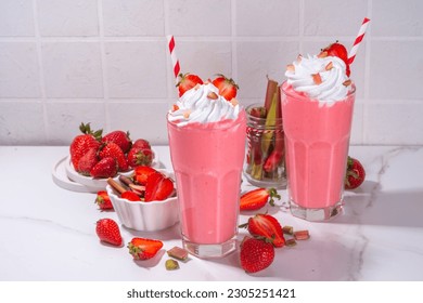 Rhubarb and strawberry milkshake or smoothie, refreshing summer drink, Healthy dieting and antioxidant summer beverage with whipped cream, fresh rhubarb, strawberry slices, on white kitchen table