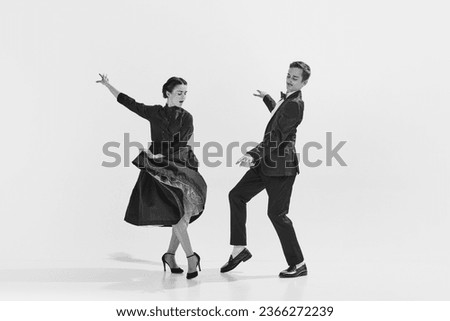 Rhythmic. Black and white. Stylish, elegant young couple, man and woman in stylus clothes dancing. Concept of hobby, retro dance, vintage style, choreography, beauty. Monochrome art. Ad