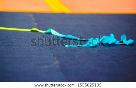 Rhythmic Gymnastics Ribbon on a carpeted surface near the gymnastics competition floor, close up. 