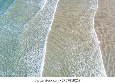 The rhythmic pattern of the ocean tide on a clean sandy coast