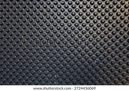 Rhythmic texture of a black polymer membrane with uniform dome-shaped studs for waterproofing and drainage. The durable synthetic material features a matte surface with a repeating geometric pattern widely used in construction and landscape design.