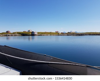 Rib Boat On Calm Blue Sea With Old Buildings And Majestic Mountains On The Helgeland Coast In Northern Norway