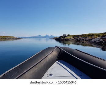 Rib Boat On Calm Blue Sea With Old Buildings And Majestic Mountains On The Helgeland Coast In Northern Norway