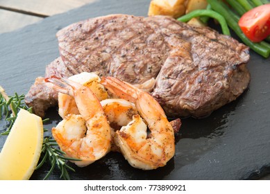 Rib Eye Steak And Grilled Shrimp On Black Plate