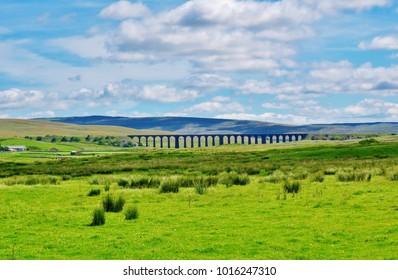 The Ribblehead Viaduct spans the Ribble Valley in North Yorkshire, England on a summer's day. In the background the looming bulk of Whernside, the highest of the Yorkshire Three Peaks, can be seen.