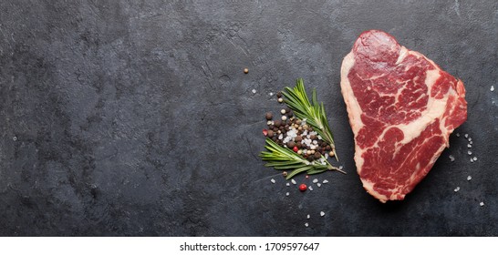 Ribeye fresh raw beef steak with spices on stone board. Top view flat lay with copy space - Shutterstock ID 1709597647