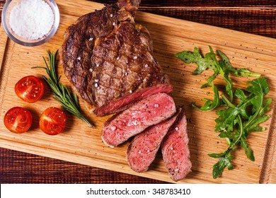 Ribeye Steak With Arugula And Tomatoes On Dark Wooden Background.