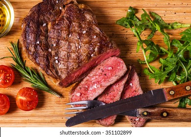 Ribeye Steak With Arugula And Tomatoes On Dark Wooden Background.