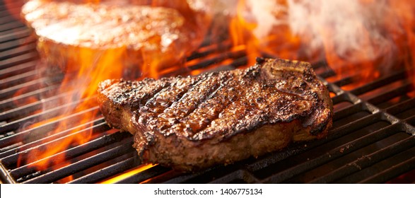 rib-eye steaks cooking on flaming grill panorama - Shutterstock ID 1406775134