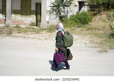 Ribnovo, Bulgaria - August 04, 2021: A Muslim woman in colorful clothes returns to the village from a market in the big district city