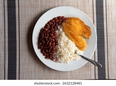 Arroz y frijoles acompañados de un filete de tilapia empanizado. Almuerzo costarricense saludable.