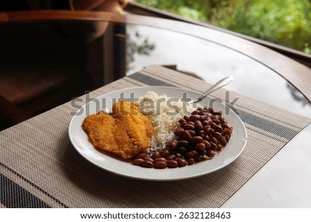 Rice and beans accompanied by a breaded tilapia fillet. Healthy Costa Rican lunch.