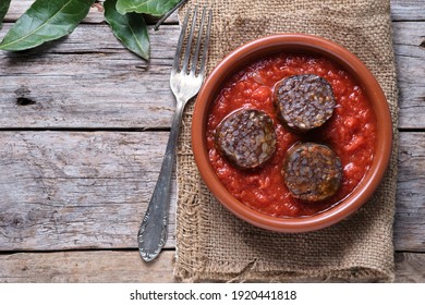 Rice blood sausage with tomato in clay pot on rustic wooden table and copy space