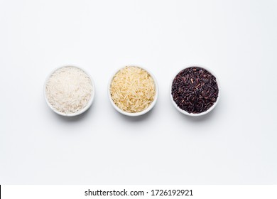 Rice bowls top view white background. 3 varieties of rice, white jasmin, basmati and black rice in white bowls on white background with copy space. Rice is the most consumed staple food ingredient.