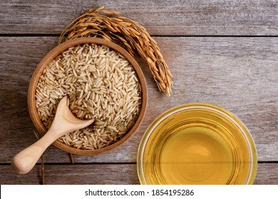 Rice bran oil extract with paddy and brown rice on wood table background. Top view. Flat lay.