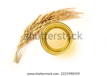 Rice bran oil in glass bowl with rice ears isolated on white background. Top view