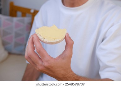 rice cake with butter held by person in white shirt, symbolizing simplicity and mindful eating habits, Healthy eating concept - Powered by Shutterstock