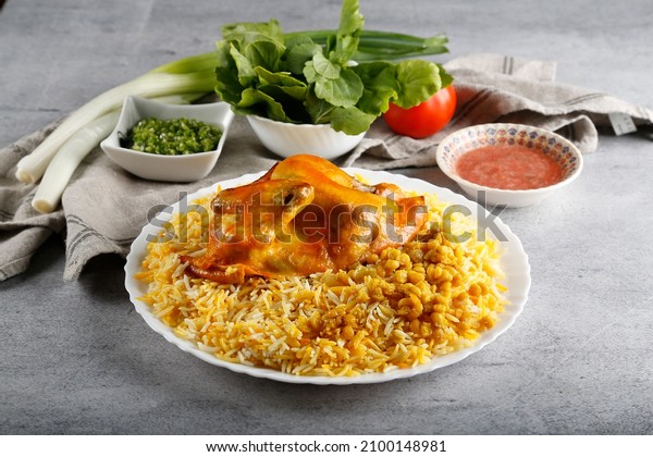 Rice and Chicken on top with tomato sauce in white plate, Biryani, majboos, kabsah, qoze.