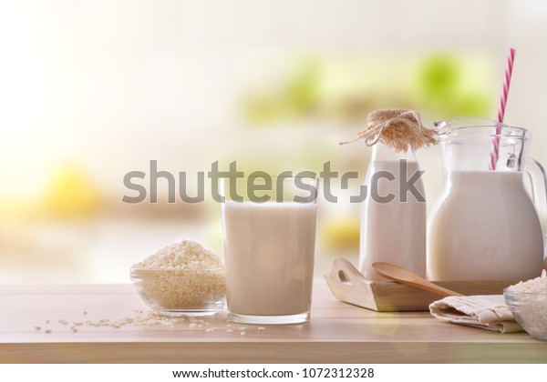 Rice drink in\
containers on a wooden table in a kitchen. Alternative milk. Front\
view. Horizontal\
composition