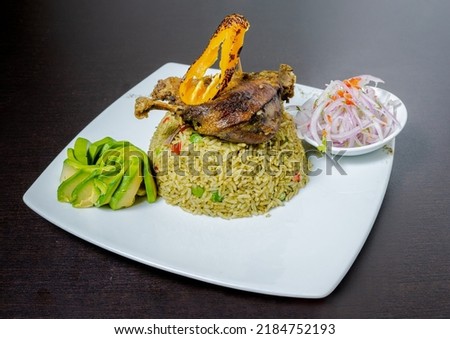 Rice with duck, accompanied by onion, lemon and lettuce. Peruvian food. White background.