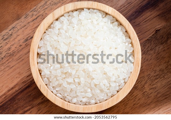 Rice grains in wooden\
bowl on wooden background, Japanese rice grains in wooden bowl on\
wooden background.