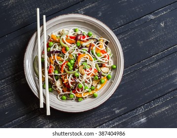 Rice noodles with vegetable stir fry on the ceramic plate on dark wooden background - Shutterstock ID 387404986