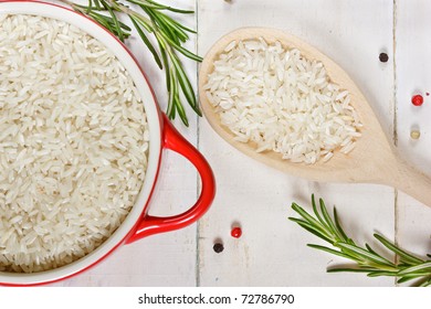 Rice in a red ceramic saucepan and a wooden spoon. - Powered by Shutterstock