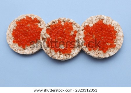 Rice round bread with red caviar on blue background
