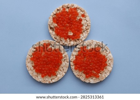 Rice round bread with red caviar on blue background