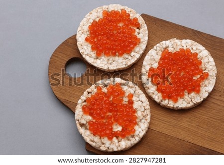 Rice round bread with red caviar on wooden board