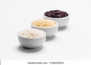 Rice the staple food of the world. 3 varieties of rice, white jasmin, basmati and black rice in white bowls on white background with copy space. Rice is the most consumed staple food ingredient.