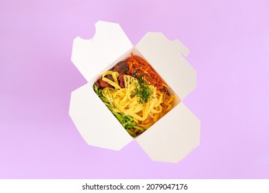 Rice Wok With Seafood And Vegetables In White Box Isolated On Purple Background, Top View. One Open Takeout Box With Rice Wok, Seafood Cocktail And Vegetables. Asian Food, Fast Food Delivery Concept