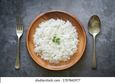 Rice in wooden plate on table top view.