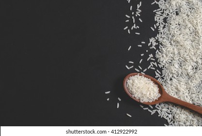 Rice and wooden spoon on black background - Shutterstock ID 412922992