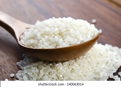 Rice in wooden spoon on kitchen table