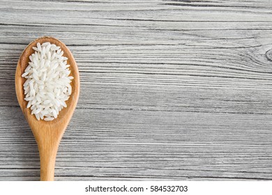 Rice in the wooden spoon on the wooden table. Healthy eating and lifestyle.