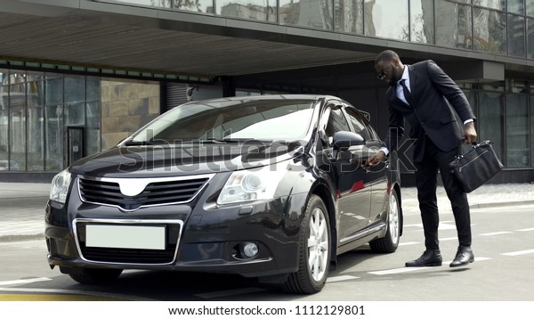 Rich African American man opening door of luxury\
car with special key,\
security