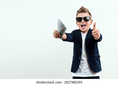 A rich boy in glasses holds dollars against the background of falling banknotes. knows how to make money. Money rain, Financial education, young millionaire, investments, loans, winnings