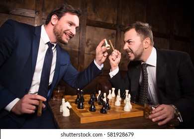Rich businessmen playing chess demonstrating rivalry or competition. Two executive men have competition between their enterprises, companies, firms. Big business concept.