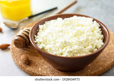 Rich in calcium healthy food. Tvorog, farmers cheese, curd cheese or cottage cheese in a bowl with honey and almond on stone table.