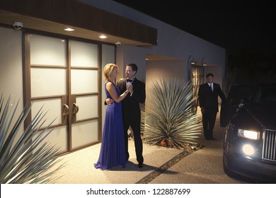 Rich Couple Dancing By Doorway Of House Ready To Leave At Night